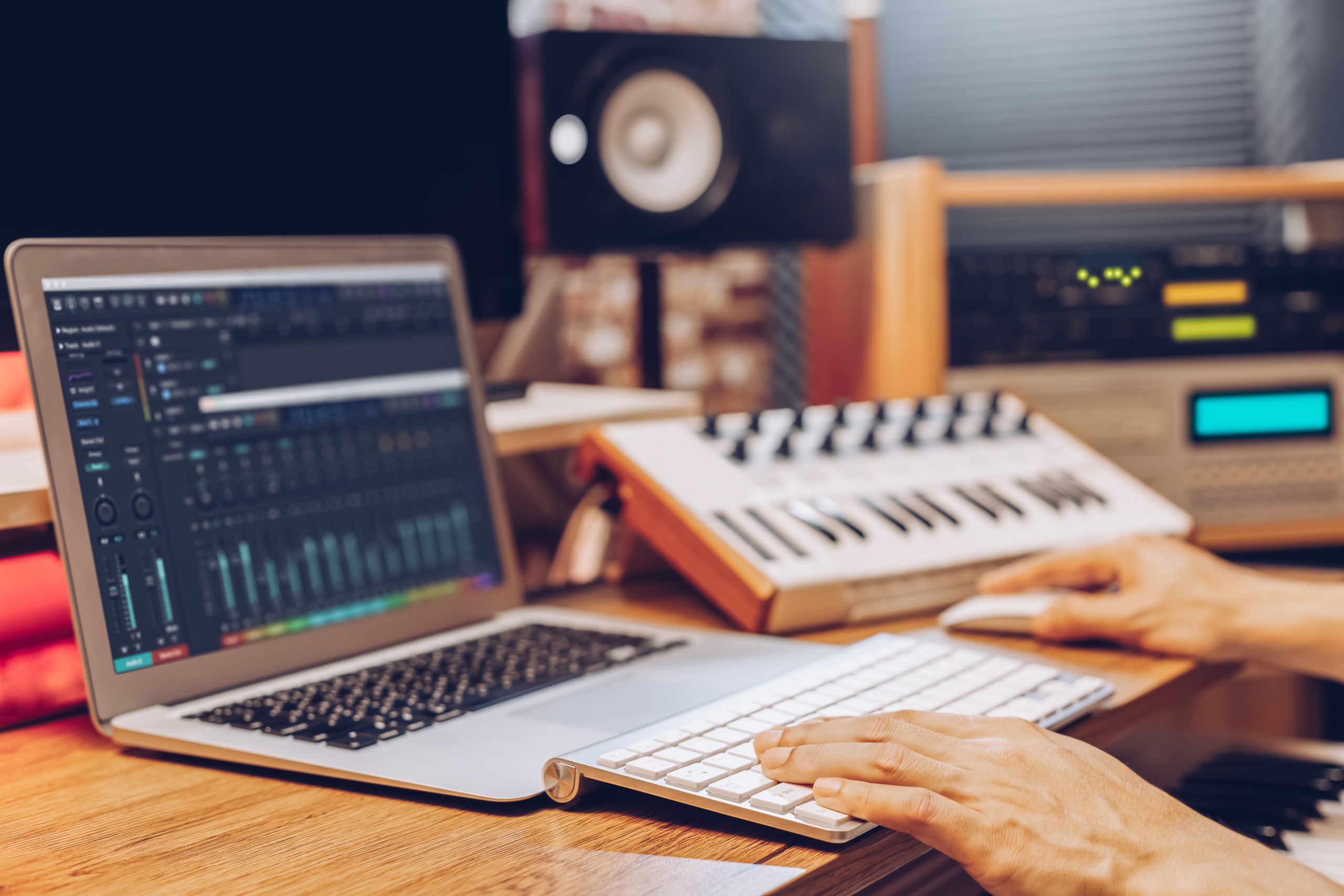 Ordinateur affichant un logiciel de mixage devant un contrôleur audio dans un home studio