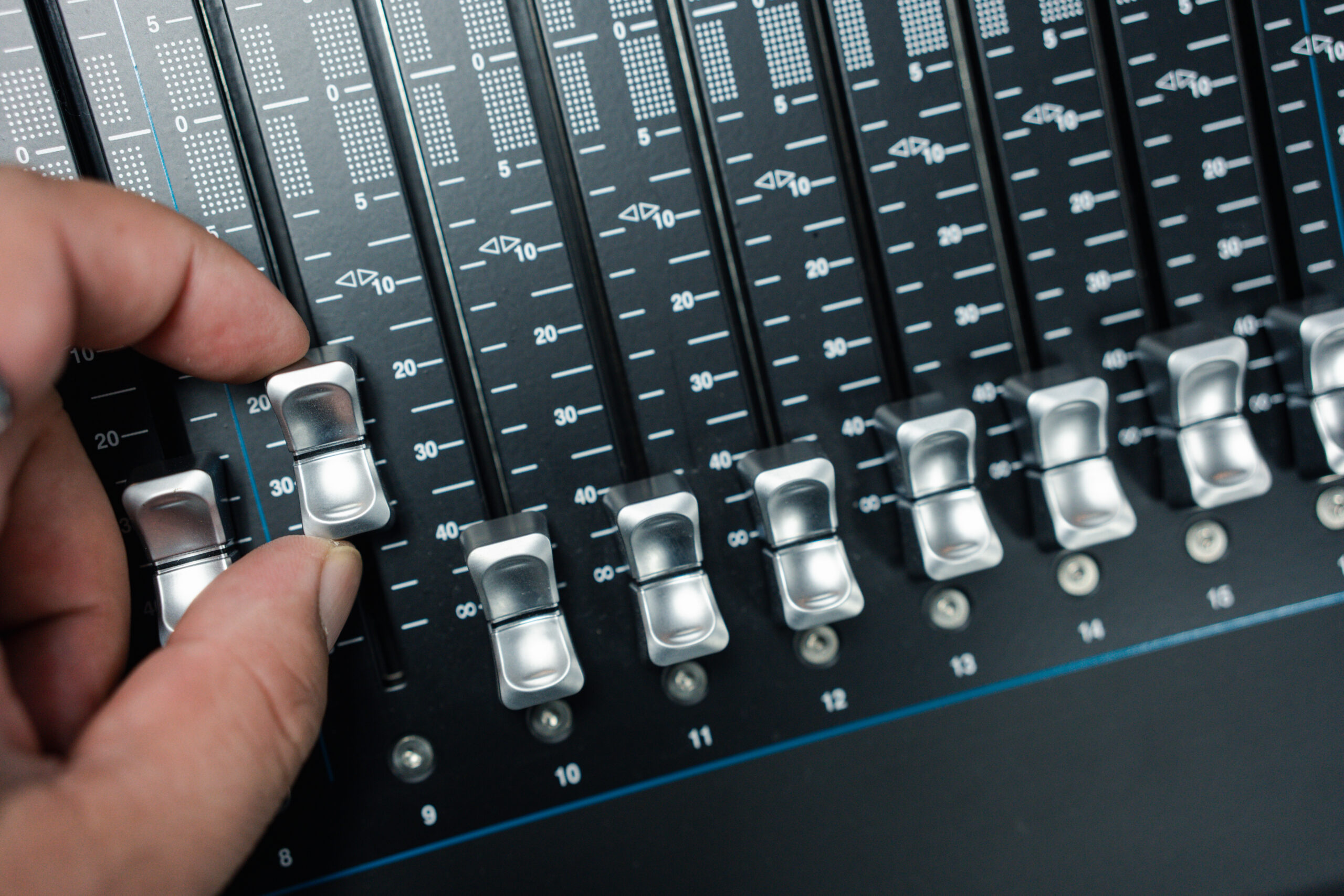 Main manipulant les potentiomètres d’une table de mixage