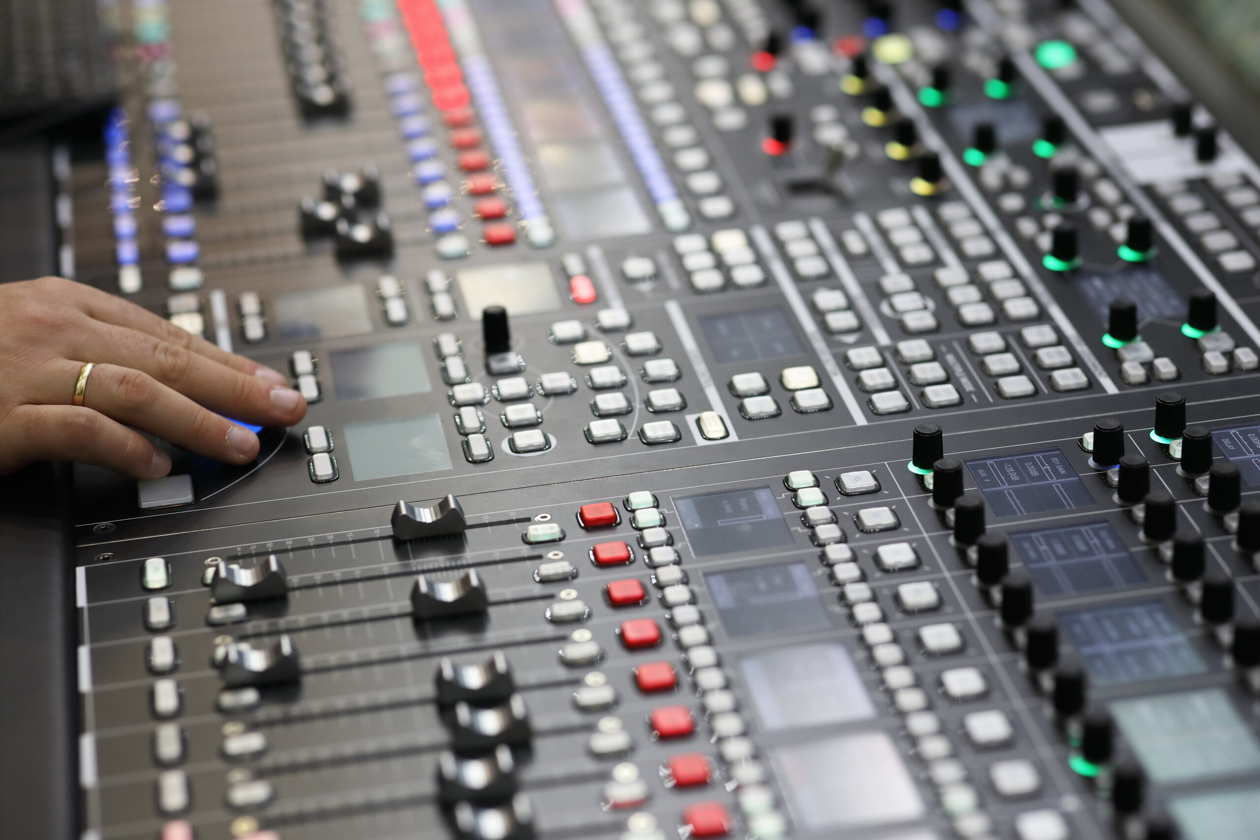 Main réglant les commandes d’une console de diffusion audio