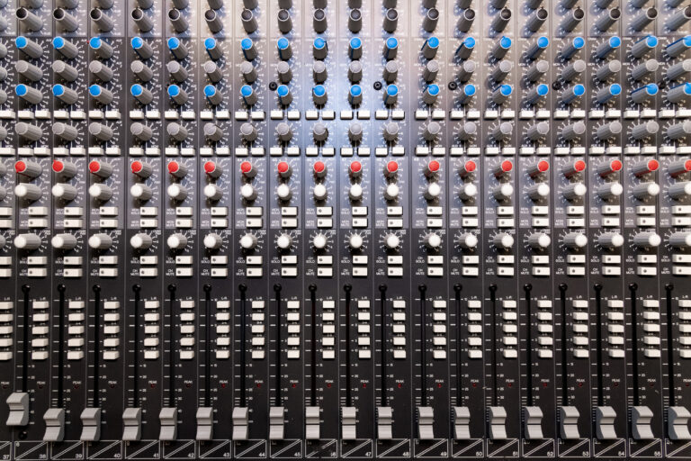 Rangées de faders et potentiomètres sur une console de mixage