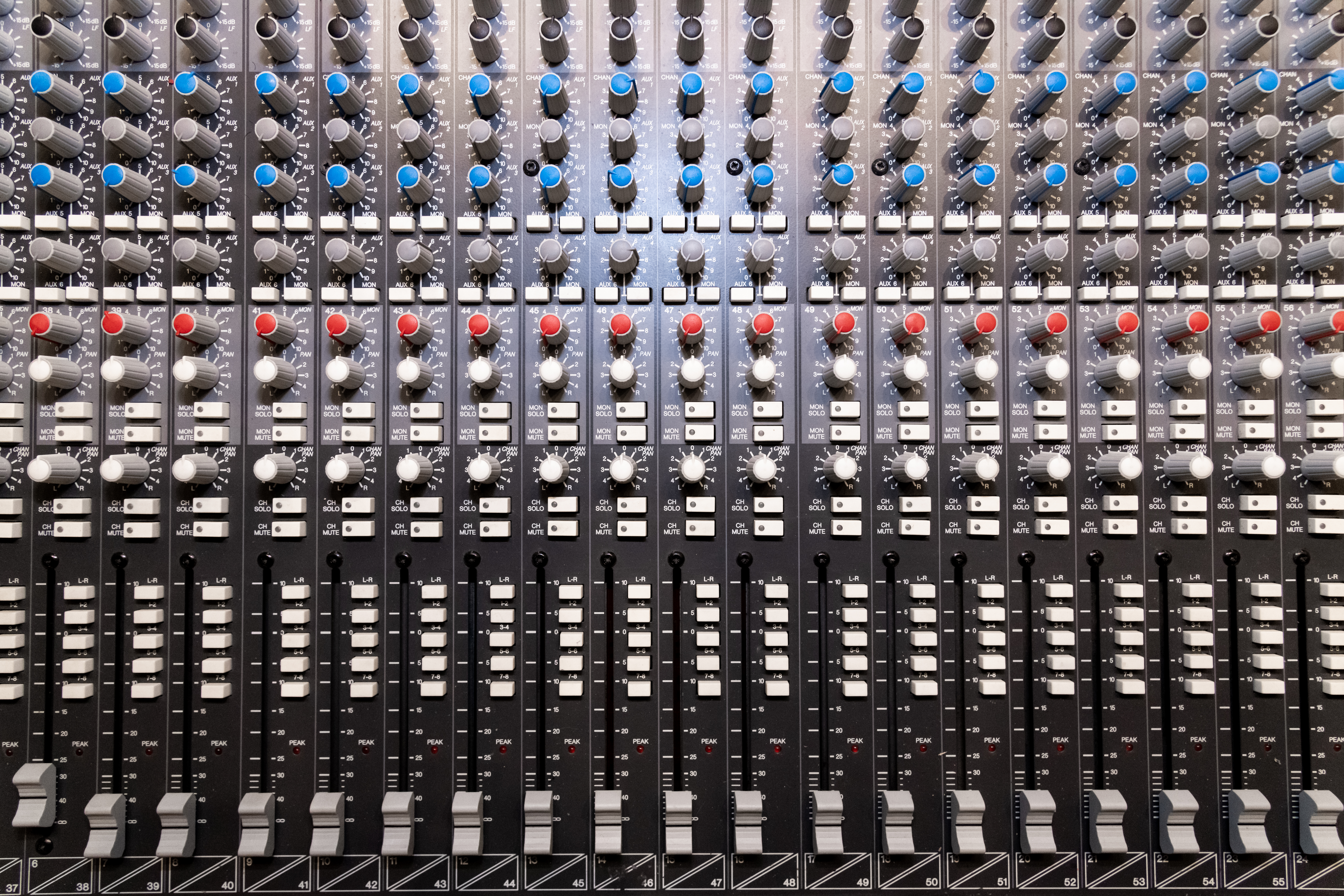 Rangées de faders et potentiomètres sur une console de mixage